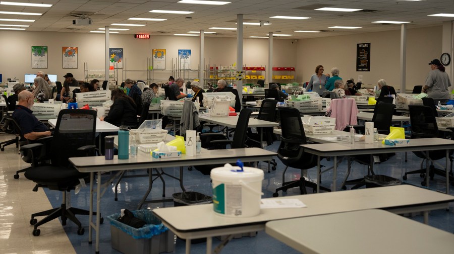 Election officials work on mail ballots at the Maricopa County Tabulation and Election Center.