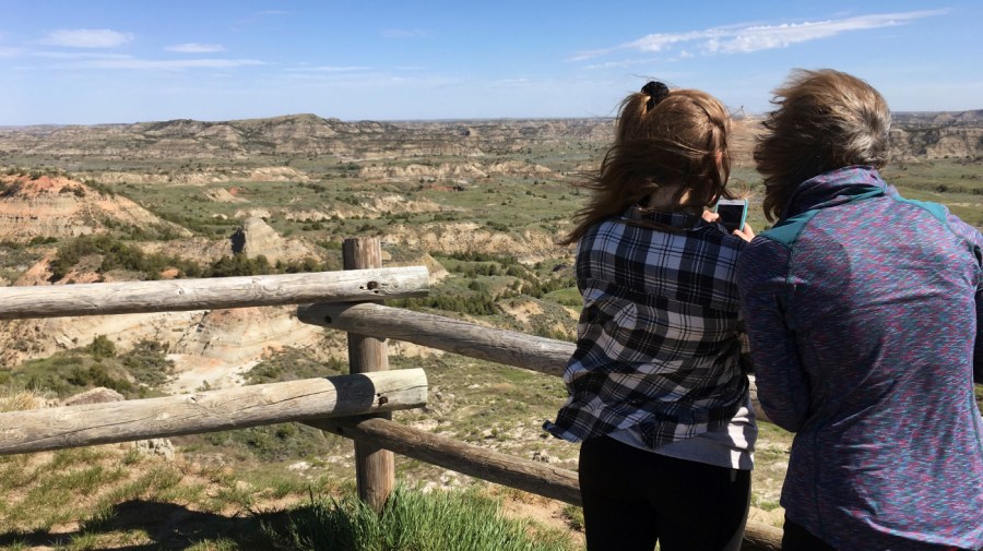 In this Wednesday, May 24, 2017, file photo, Jeanne Randall, right, and her daughter Zoe, of Shoreview, Minn., take photos at Painted Canyon in Theodore Roosevelt National Park in western North Dakota.