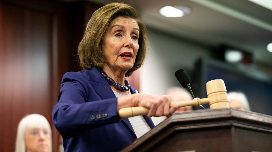 Representative Nancy Pelosi holds a gavel as she speaks at a press conference.