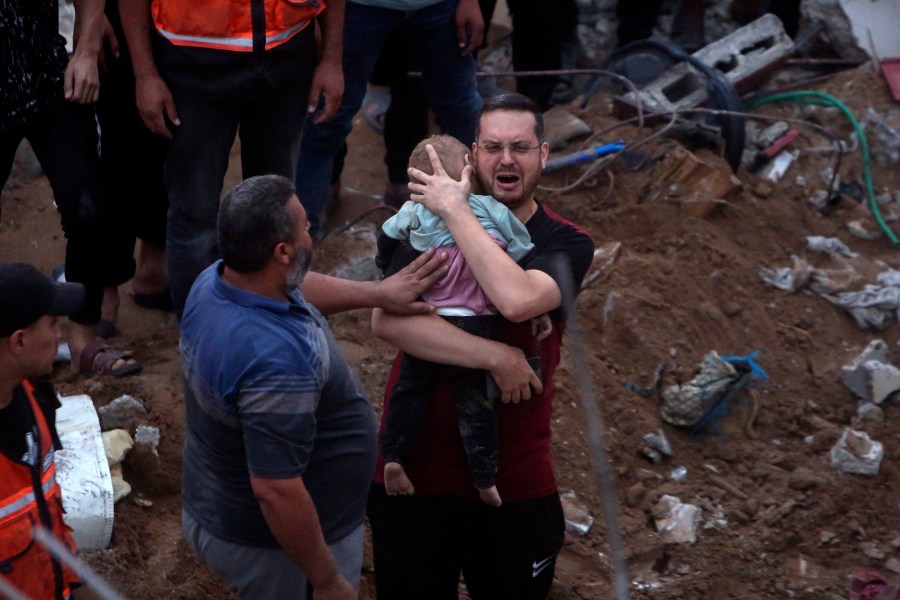 FILE - A Palestinian man cries while holding a dead child who was found under the rubble of a destroyed building following Israeli airstrikes in Nusseirat refugee camp, central Gaza Strip on Oct. 31, 2023. On Thursday, April 4, 2024, Human Rights Watch says an Israeli attack on a Gaza apartment building in October killed at least 106 civilians, including 54 children. (AP Photo/Mohammed Dahman, File)