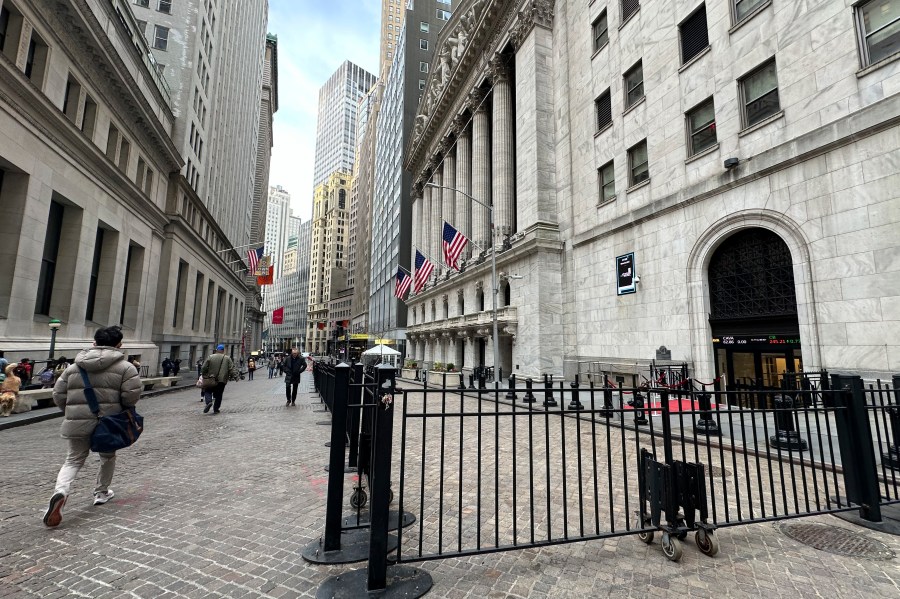 People pass the New York Stock Exchange, right, on Wednesday, April 17, 2024 in New York. Global shares are trading mixed after most U.S. stocks slipped on firmer expectations that the Fed is committed to its current rate practices.(AP Photo/Peter Morgan)