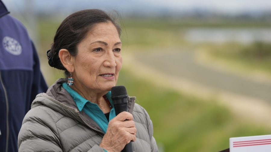 Interior Secretary Deb Haaland speaks against the backdrop of a wildlife refuge at an event.