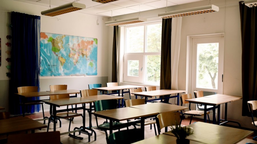 Desks are arranged in an empty classroom.