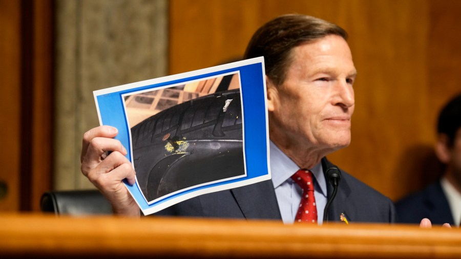 Senator Richard Blumenthal holds up a photo of a punctured tire while questioning Boeing whistleblower Sam Salehpour.