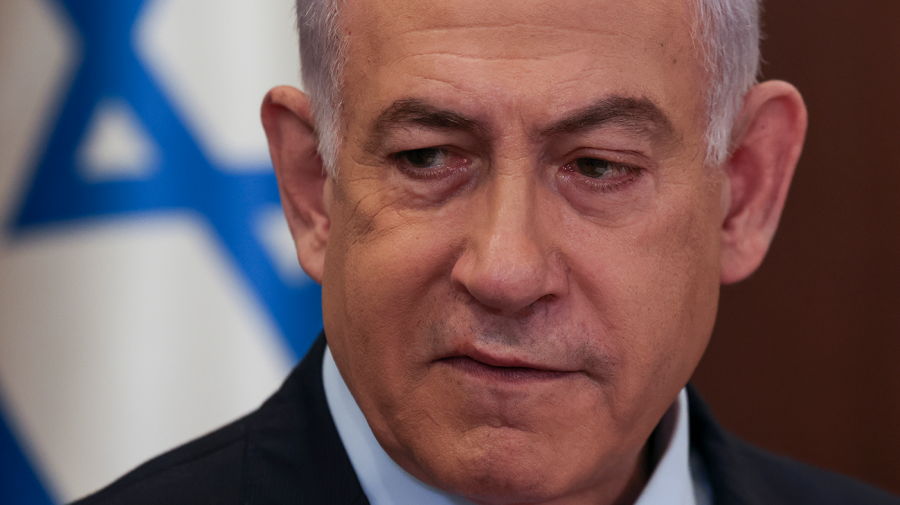 Israeli Prime Minister Benjamin Netanyahu is seen in a close-up in front of an Israeli flag.