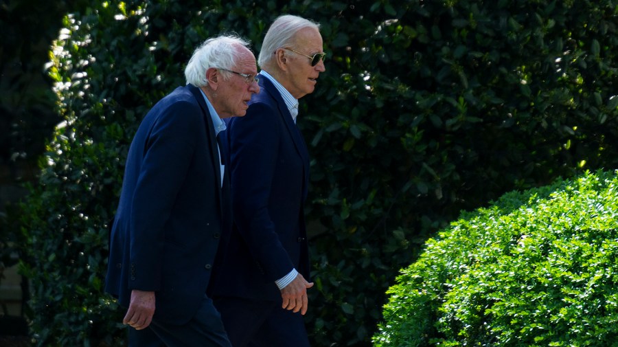 Senator Bernie Sanders walks at the White House with President Joe Biden.