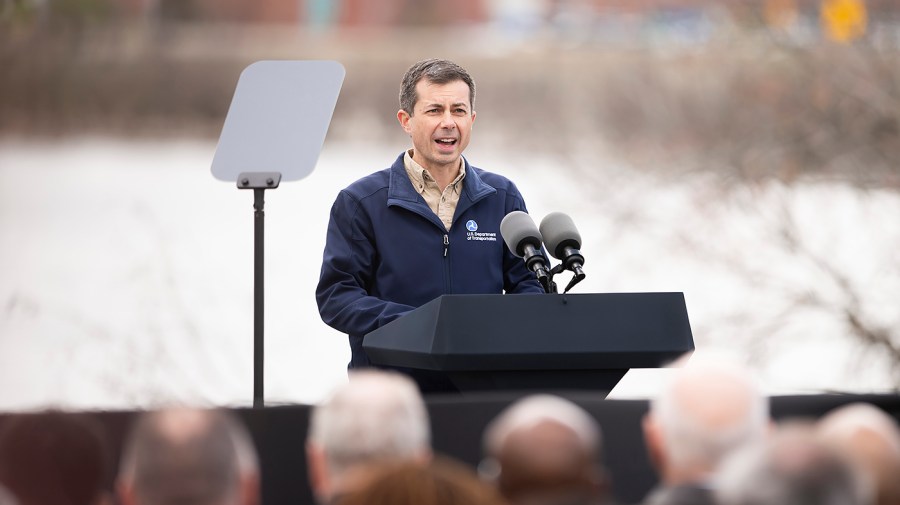 Transportation Secretary Pete Buttigieg speaks outside at an event.