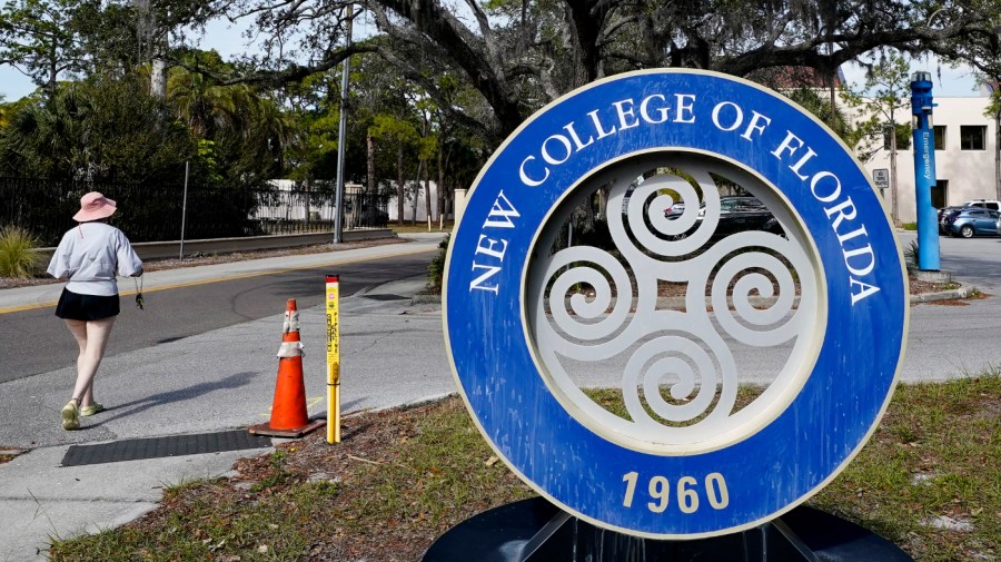 A student makes her way past the sign at New College of Florida.