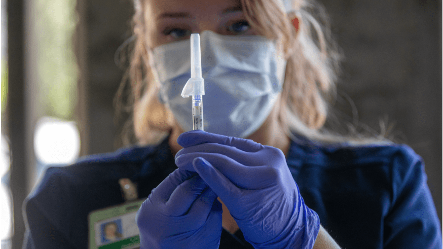 A medical professional prepares a syringe.