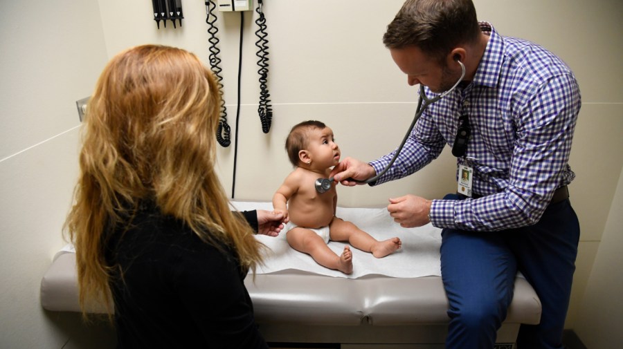 Physician's assistant Ryan Conrad listens to patient America Montes, 8-months-old, as her mother Nancy Espino, left, holds her hand during a well-baby checkup at the Denver Health Sam Sandos Westside Health Center January 25, 2018.