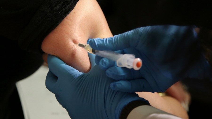 A woman receives a vaccine in her arm.