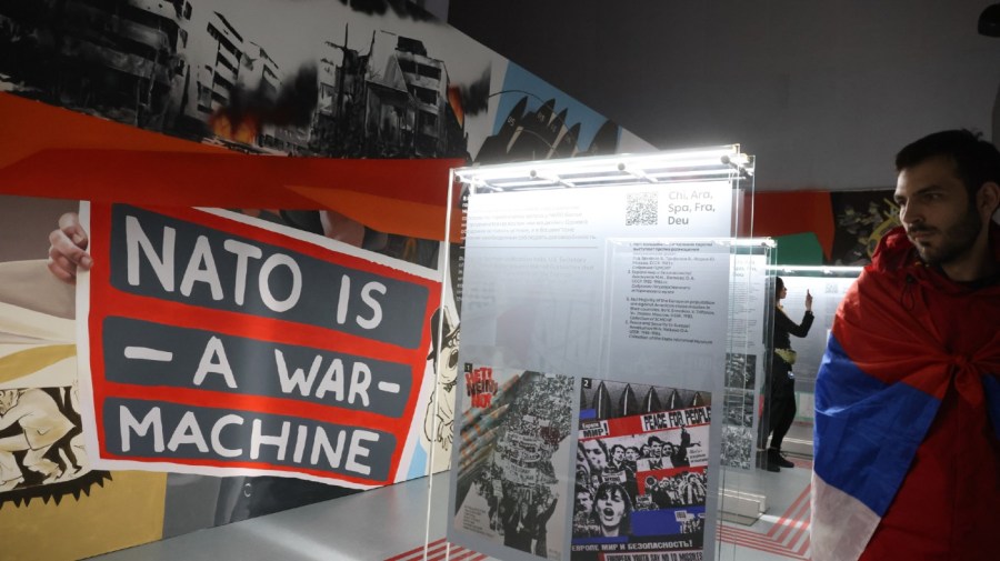 A participant from Serbia looks at a poster with sign reads "NATO is a war machine", while visiting a a propaganda exhibition called "NATO. History of deception. History of evil", during the International Youth Festival on March 6, 2024 in Sirius Federal Territory, Sochi, Russia.