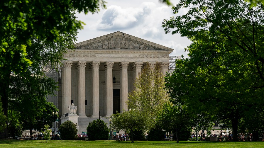 Supreme Court is seen in the distance surrounded by trees and greenery.