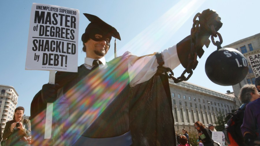 In this Oct. 6, 2011 photo, Gan Golan, of Los Angeles, dressed as the "Master of Degrees," holds a ball and chain representing his college loan debt, during Occupy DC activities in Washington.