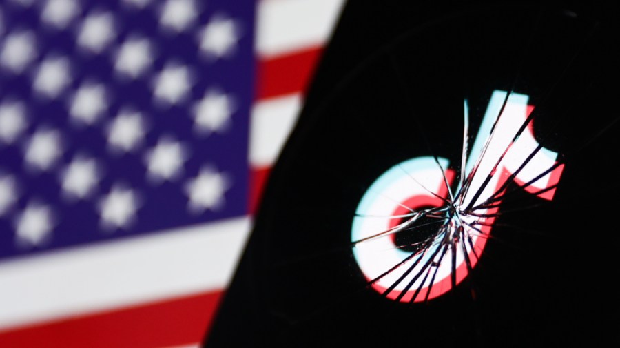 TikTok logo displayed on a phone screen is seen through the broken glass with American flag displayed on a screen in the background in this illustration photo taken in Krakow, Poland on April 24, 2024.