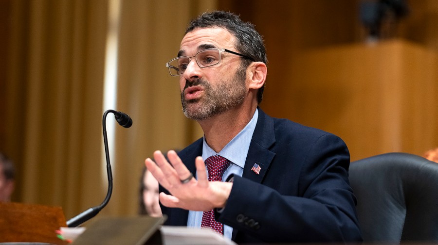 IRS Commissioner Danny Werfel holds out his hand while speaking at a congressional hearing.