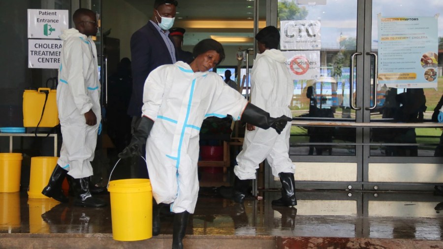 A worker carries a bucketfull of disinfectant at a cholera treatment centre, in Lusaka, Zambia, Friday, Jan 12, 2024.