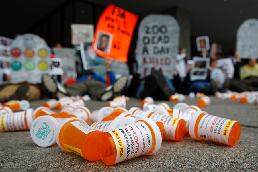 Orange prescription pill bottles are scattered on the ground.