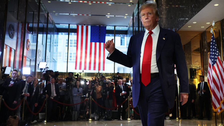 Former President Trump holds up a fist while passing reporters.