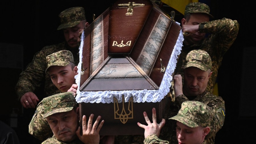 Ukrainian soldiers carry a coffin