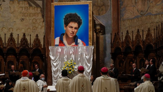 People watch as an image of 15-year-old Carlo Acutis is unveiled during his beatification ceremony.