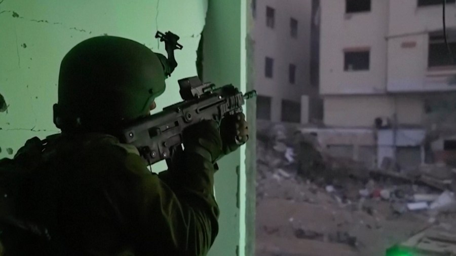 In this image taken from a video released by the Israeli Defense Forces on Tuesday, Nov. 14, 2023, an Israeli soldier holds a weapon in Gaza City.