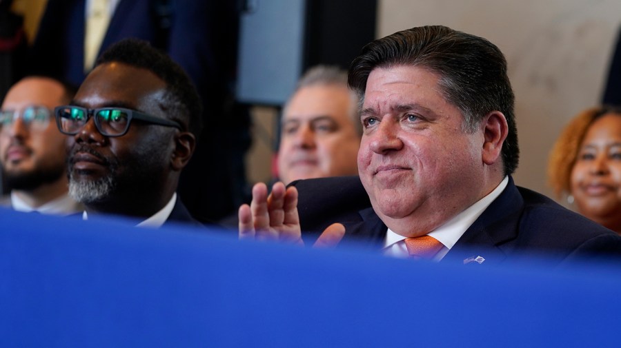 Chicago Mayor Brandon Johnson and Illinois Gov. JB Pritzker applaud while at an event.