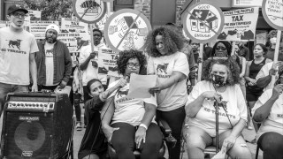 Tenant organizer Tara Raghuveer holds a microphone up to a speaker during a meeting of the KC Tenants tenant union in Kansas City, Missouri, in May 2021.