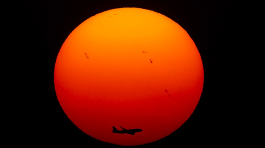 A commercial aircraft approaches the runway as the sun sets for the last time in 2022, in New Delhi, India, Saturday, Dec. 31, 2022.