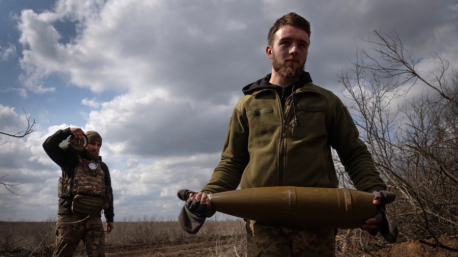 Ukrainian soldiers carry shells to fire at Russian positions on the front line.