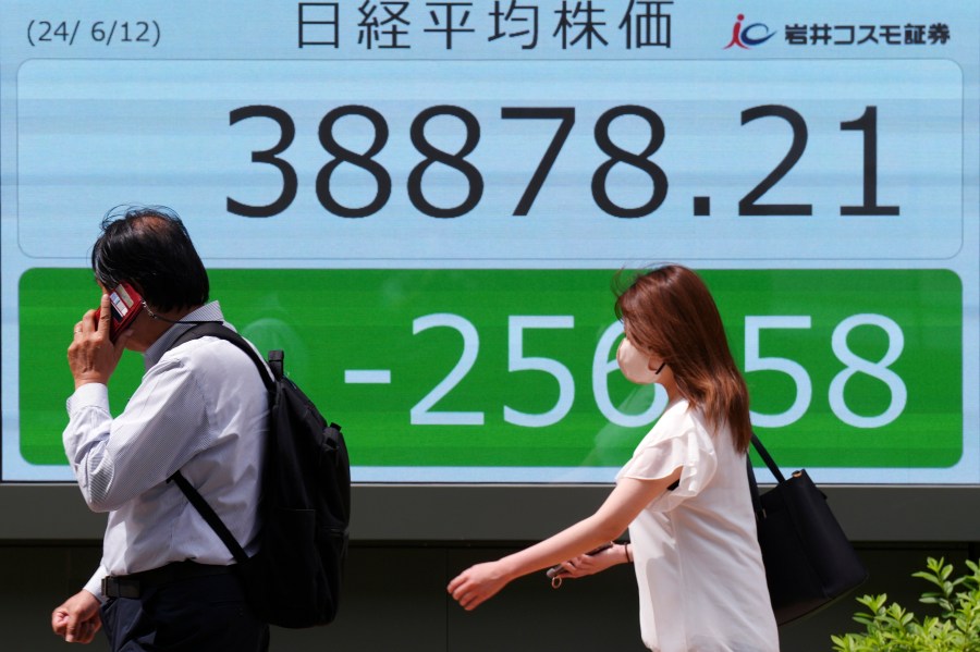 People walk in front of an electronic stock board showing Japan's Nikkei 225 index at a securities firm Wednesday, June 12, 2024, in Tokyo. (AP Photo/Eugene Hoshiko)