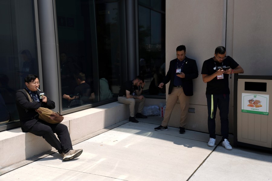 Smokers try and find shelter from the sun at the Collision Conference as temperatures soar in Toronto, Tuesday, June 18, 2024. (Chris Young/The Canadian Press via AP)