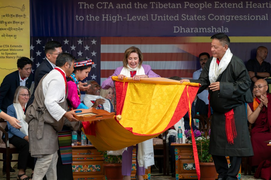 Democratic former House Speaker Nancy Pelosi, center, is presented with a Tibetan traditional Buddhist painting called Thangka by the President of the Central Tibetan Administration, Penpa Tsering, right, at a public event during which a US delegation led by Republican Rep. Michael McCaul was felicitated by Tibetan exiled government officials at the Tsuglakhang temple in Dharamshala, India, Wednesday, June 19, 2024. (AP Photo/Ashwini Bhatia)