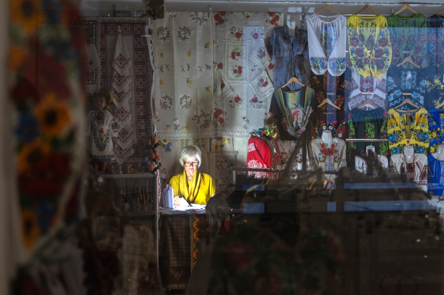 A seller shines a flashlight during a power outage in an underground shopping mall in central Kyiv, Ukraine, Wednesday, June 19, 2024. Russian regular massive missile attacks against Ukraine's energy facilities have resulted in electricity supply restrictions having been applied throughout the country. (AP Photo/Efrem Lukatsky)