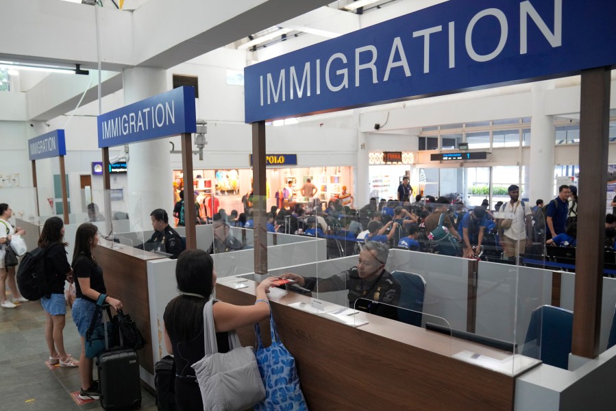 FILE - Officers check the passports of passengers leaving for Singapore at the immigration checkpoint of the Bandar Bentan Telani ferry terminal on Bintan Island, Indonesia, Wednesday, May 15, 2024. Indonesian authorities said Monday that the country's national data center was compromised by a cyber attack, disrupting public services including the immigration check points and asked for an $8 million ransom. (AP Photo/Dita Alangkara, File)