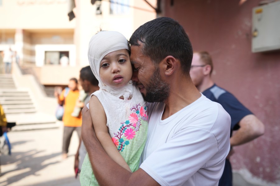 A Palestinian man reacts as he says goodbye to his sick daughter before leaving the Gaza Strip to get treatment abroad through the Kerem Shalom crossing, in Khan Younis, southern Gaza Strip, Thursday, June 27, 2024. 21 patients in the Gaza Strip evacuated the war-torn enclave in an initiative led by the World Health Organization for the children to receive life-saving treatment elsewhere. (AP Photo/Abdel Kareem Hana)