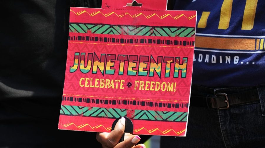 A person holds up a Juneteenth sign that says "Celebrate Freedom!"