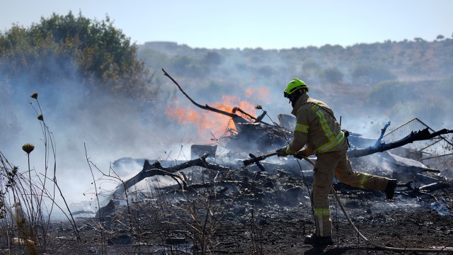 A firefighter works on putting out a fire burning near debris.