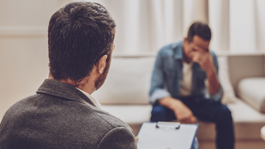 A counselor speaks to a man in distress.