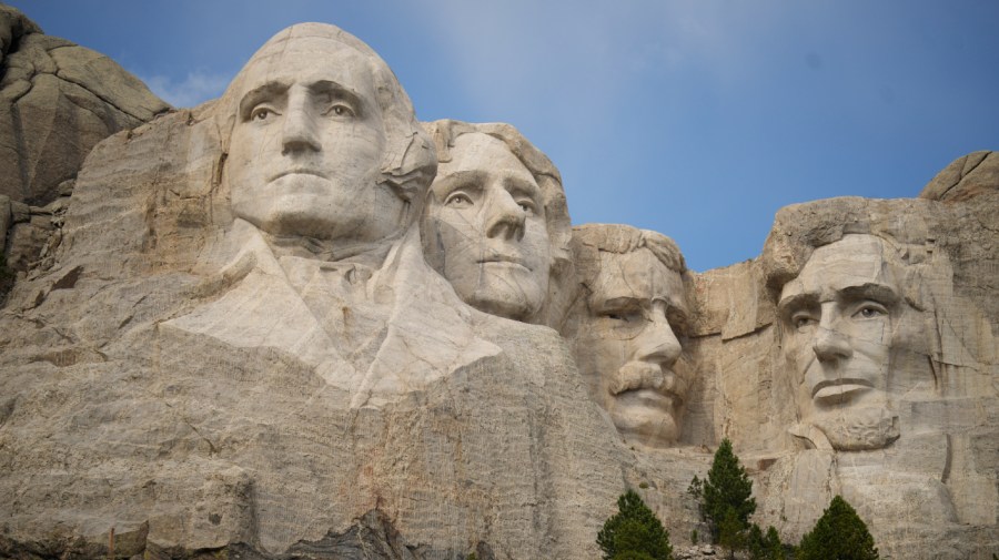 The sculptures at Mount Rushmore are seen on a clear day in front of a blue sky.