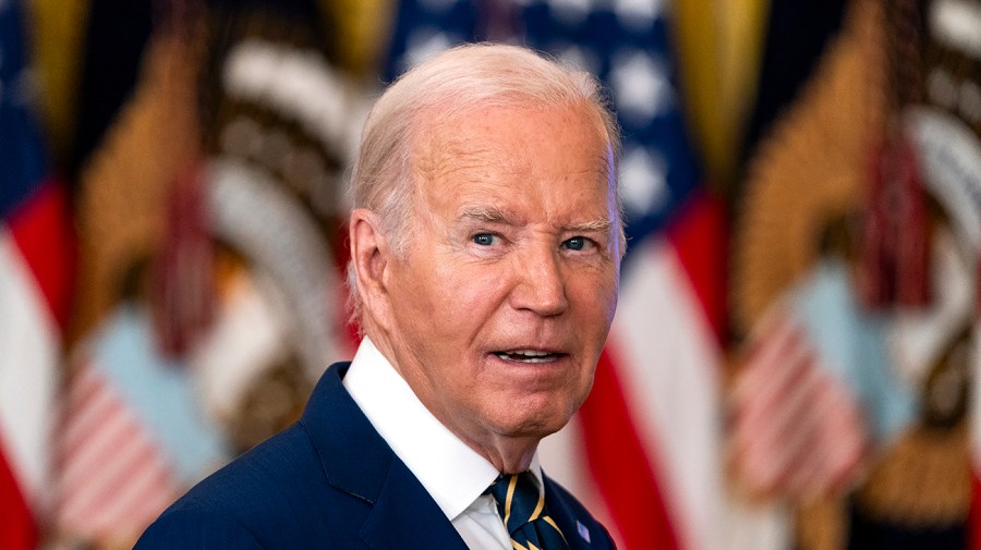 President Biden is seen in front of some American flags.