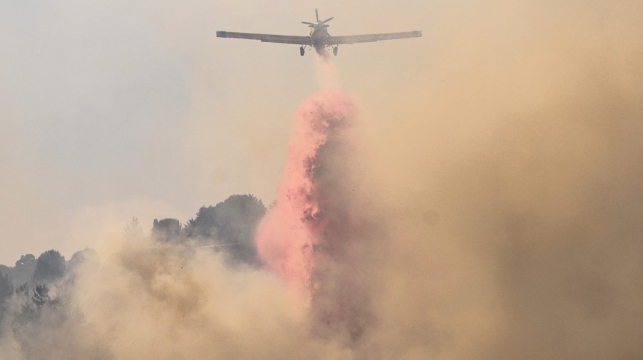 A plane tries to extinguish a fire while flying through a plume of smoke.