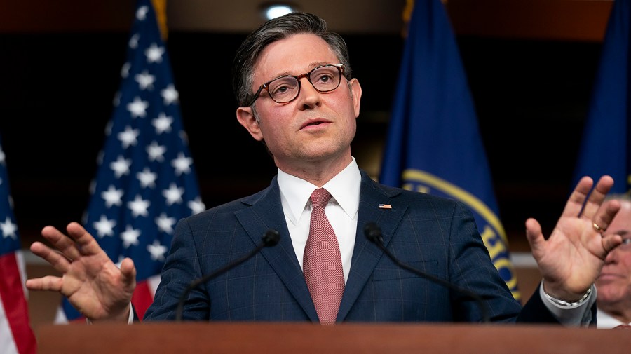 Speaker Mike Johnson gestures while speaking at a podium.