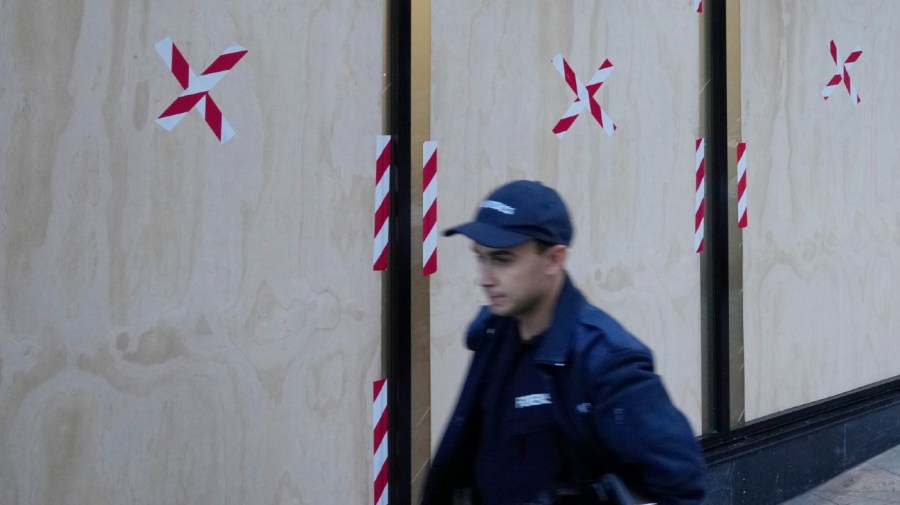 A forensic officer walks past boarded windows at the U.S. consulate as police investigate the vandalism in Sydney, Monday, June 10, 2024. A suspect is believed to have smashed nine holes in the reinforced glass windows of the building in North Sydney after 3 a.m., a police statement said.