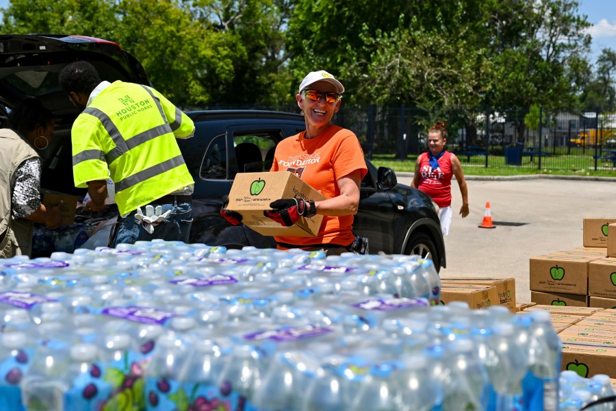 Volunteer Karen Jones, center, helps to hand out supplies at Acres Homes cooling center in Houston, Wednesday, July 10, 2024. After Hurricane Beryl slammed into Texas, knocking out power to nearly 3 million homes and businesses. (AP Photo/Maria Lysaker)