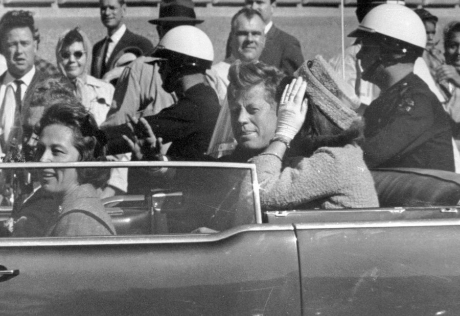 FILE - President John F. Kennedy waves from his car in a motorcade approximately one minute before he was shot, Nov. 22, 1963, in Dallas. Riding with President Kennedy are first lady Jacqueline Kennedy, right, Nellie Connally, second from left, and her husband, Texas Gov. John Connally, far left. (AP Photo/Jim Altgens, File)