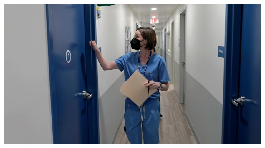 A doctor enters an exam room consult with a patient.