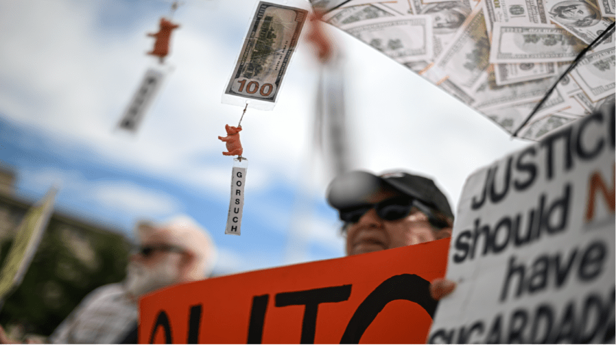 Supreme Court justice's names dangle from pig figurines and money on the umbrella of a demonstrator outside the Supreme Court as several decisions by the court are to be made on June 27, 2024 in Washington, D.C. (Photo by Ricky Carioti/The Washington Post via Getty Images)