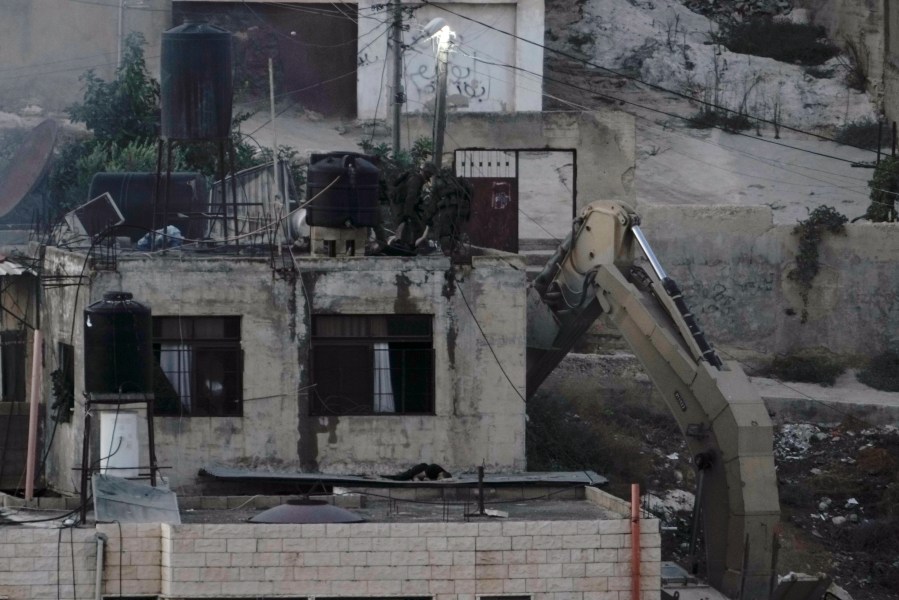 EDS NOTE: GRAPHIC CONTENT - Israeli soldiers look over a rooftop where two lie motionless in the West Bank town of Qabatiya during a raid, Thursday, Sept.19, 2024. (AP Photo/Majdi Mohammed)