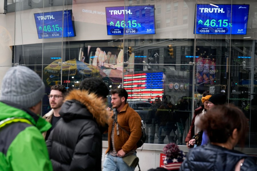 FILE - Pedestrians walk past the Nasdaq building as the stock price of Trump Media & Technology Group Corp. is displayed on screens, March 26, 2024, in New York. (AP Photo/Frank Franklin II, File)